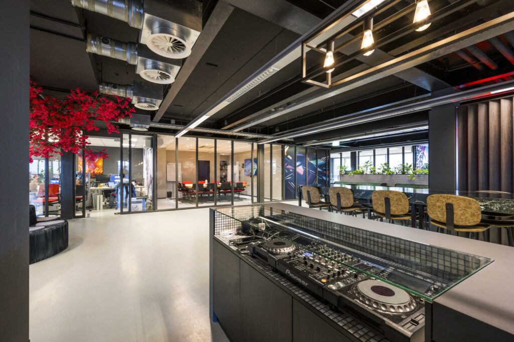 Modern kantoorinterieur aan de Anthony Fokkerweg met een DJ-booth, glazen vergaderruimtes en kleurrijke accenten.